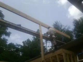 Carpenter setting a ridge beam over a new addition frame — Ice Dam Removal by Roofing Brothers in Gobles