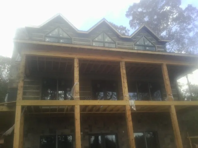 Dormers and porch framing on a large log home under construction — Roof Coating work by our crew in Gobles