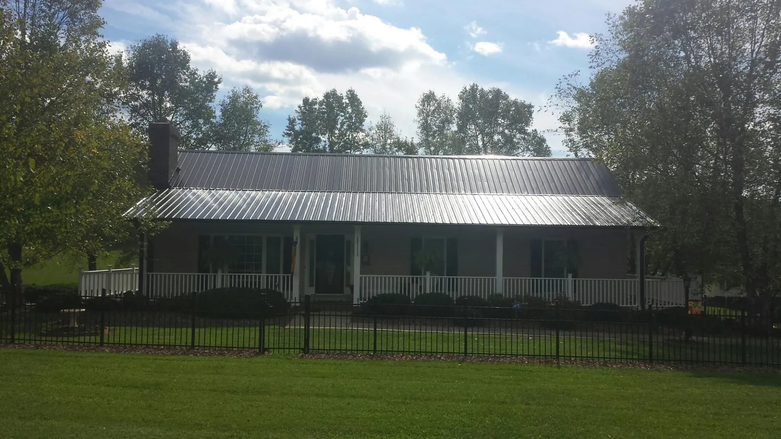 Gray metal roof on a brick ranch with a full width front porch — Gutter Guard Installation work by our crew in Gobles