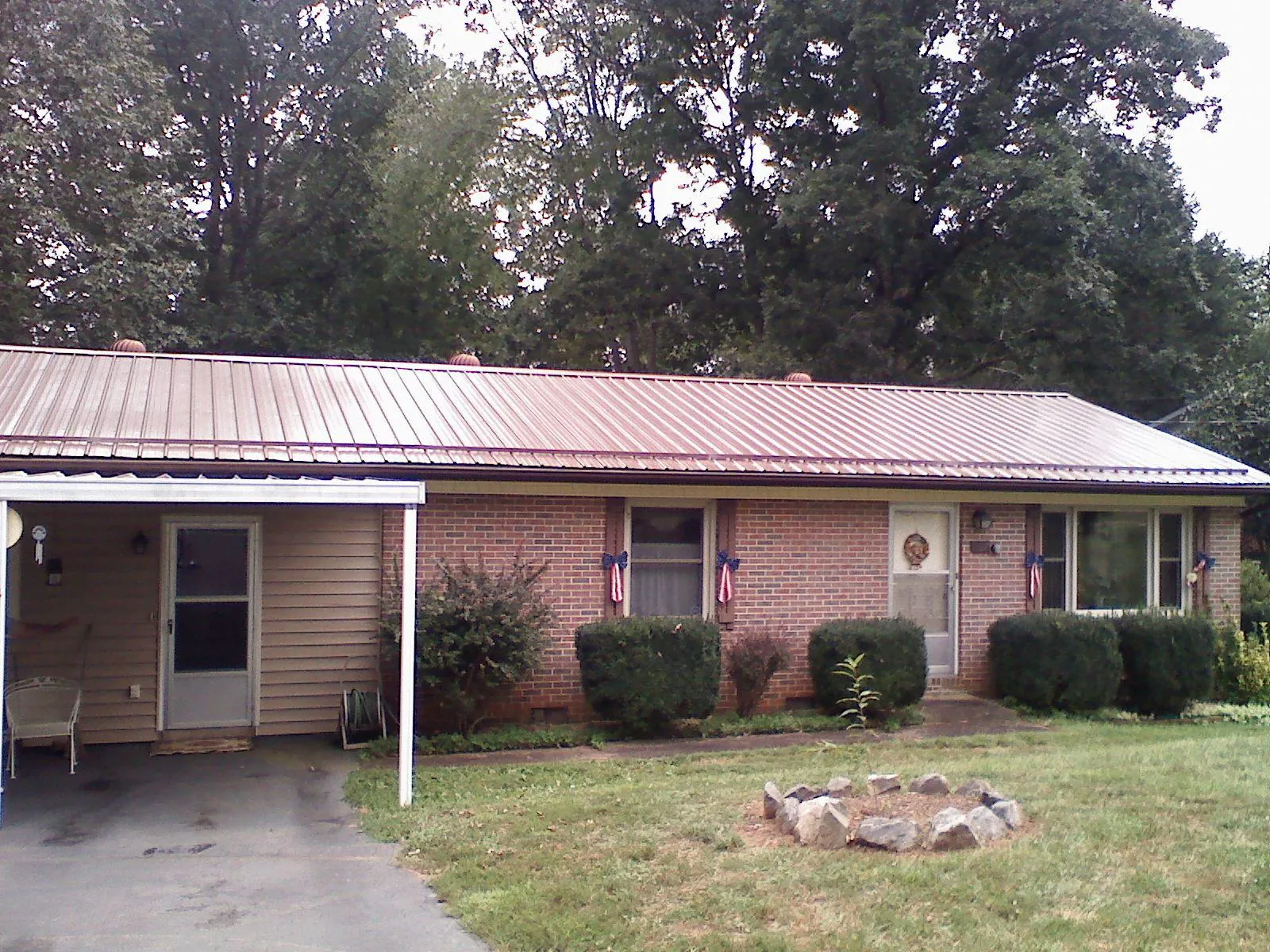 Bronze metal roof and carport on a brick ranch home — Roof Repair work by our crew in Gobles