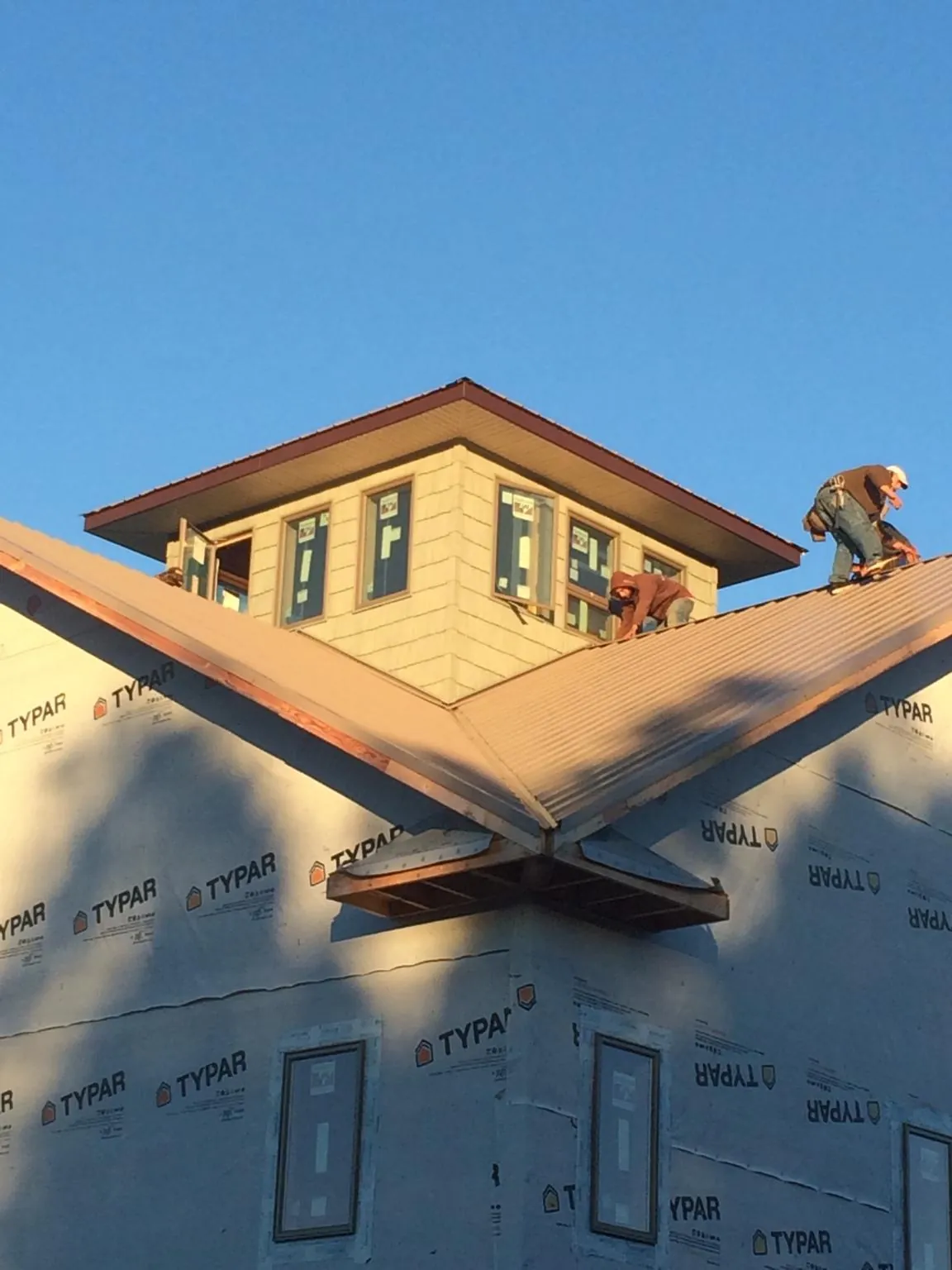 Roofers working around a rooftop cupola on a new metal roof at sunset — Roof Waterproofing in Gobles by Roofing Brothers